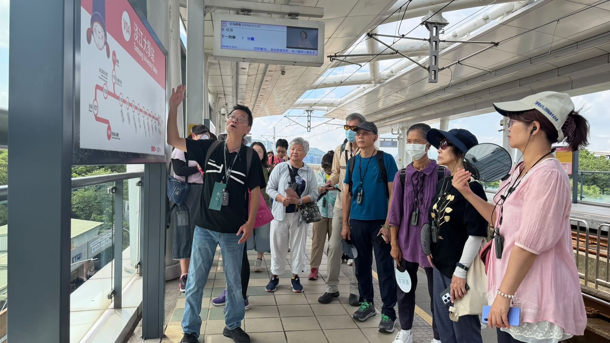 參與者在淡海輕軌月台聆聽導覽老師解說路線與站體