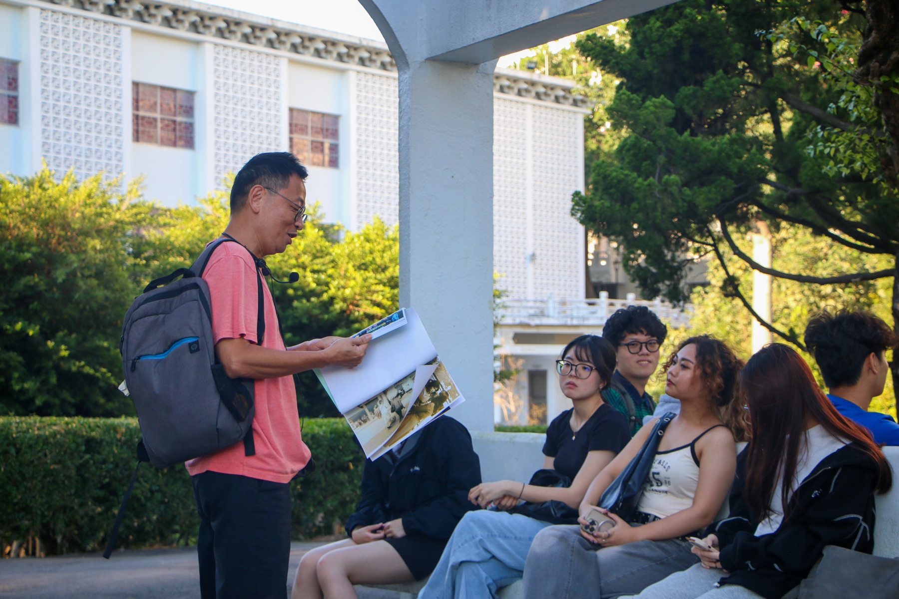 吳峻毅老師在淡江大學校園展示歷史影像，學生坐在周圍聆聽